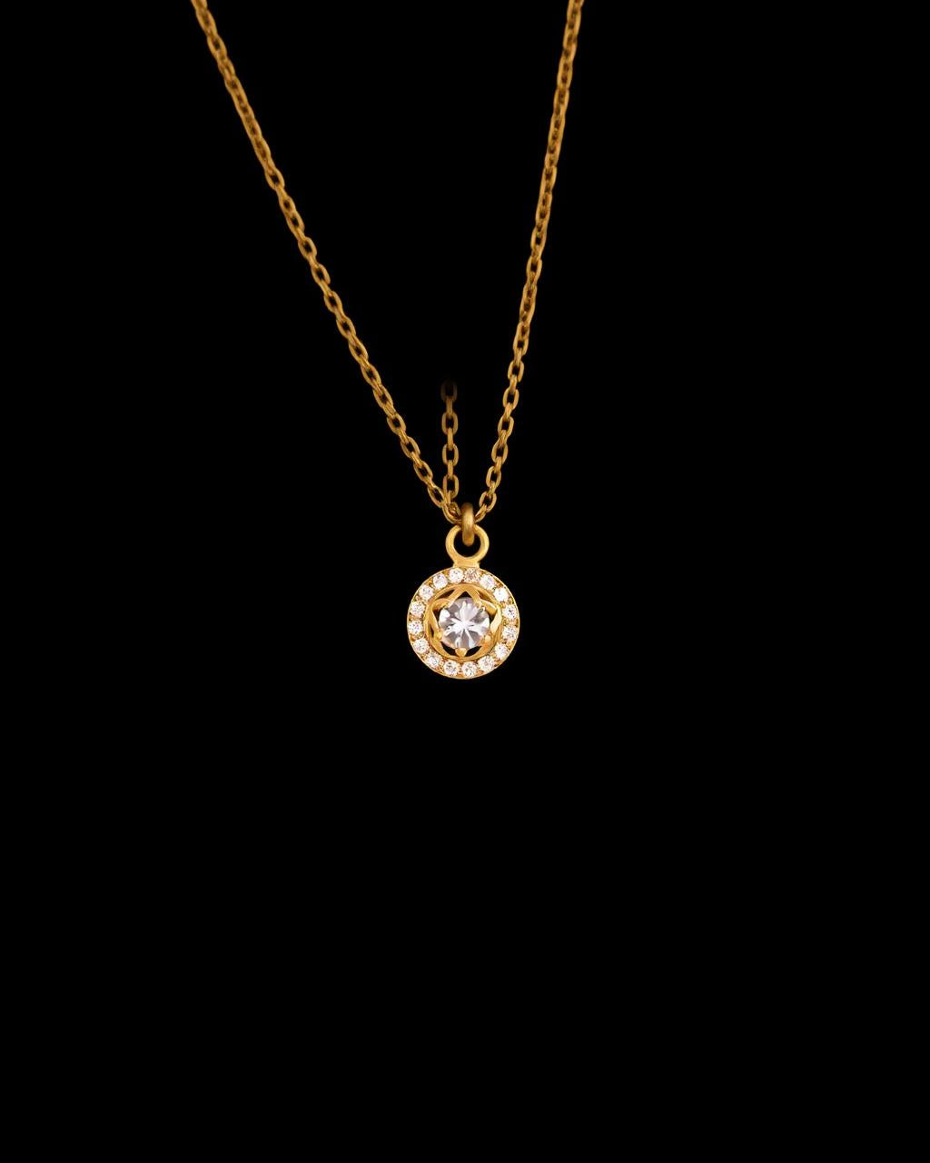 Gold halo pendant necklace lit against black